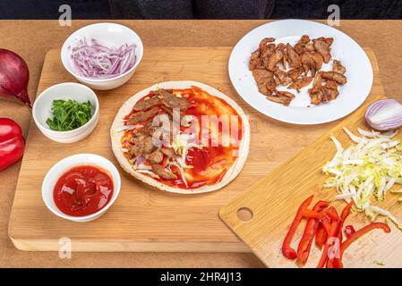 Fleischstücke und Reihen von Kohl und Zwiebeln auf einer libanesischen Pita. Kochen von Kebab zu Hause. Stockfoto