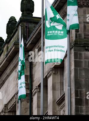 Kiel, Deutschland. 25.. Februar 2022. Vor dem Kieler Rathaus fliegen Flaggen mit der Aufschrift "Bürgermeister für den Frieden". Als Zeichen für den Frieden wird die Landeshauptstadt am Freitag, den 25. Februar und Samstag, den 26. Februar, die Flagge des internationalen Bündnisses Mayors for Peace im Rathaus aufführen. Quelle: Axel Heimken/dpa/Alamy Live News Stockfoto