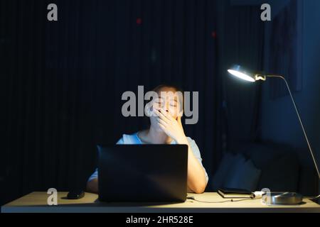 Asiatische Frau Geschäftsmann arbeitete an ihrem Laptop, um für die Präsentation morgen früh in der Nacht vorzubereiten sah sie so müde und müde, dass sie gähnte Stockfoto