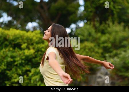 Völlig kostenlos. Aufnahme einer Frau, die die Natur mit erhobenen Armen genießt. Stockfoto