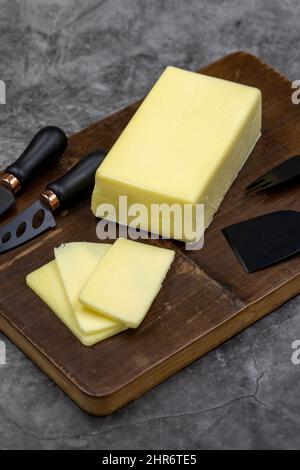 Kashar-Käse oder Kashkaval-Käse auf dunklem Hintergrund. Cheddar-Käse In Scheiben Stockfoto