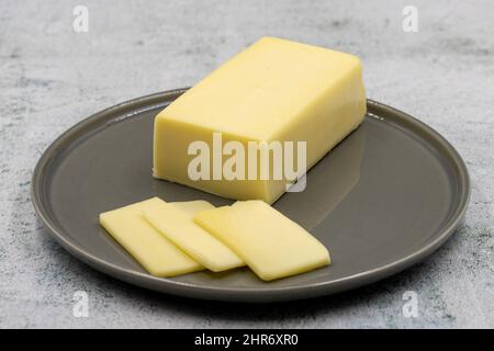 Kashar-Käse oder Kashkaval-Käse auf steinernem Hintergrund. Cheddar-Käse In Scheiben Stockfoto