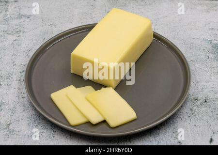 Kashar-Käse oder Kashkaval-Käse auf steinernem Hintergrund. Cheddar-Käse In Scheiben Stockfoto