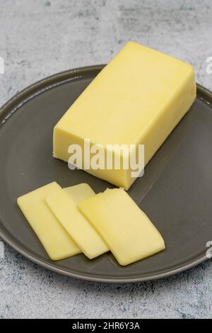 Kashar-Käse oder Kashkaval-Käse auf steinernem Hintergrund. Cheddar-Käse In Scheiben Stockfoto