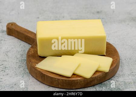 Kashar-Käse oder Kashkaval-Käse auf steinernem Hintergrund. Cheddar-Käse In Scheiben Stockfoto