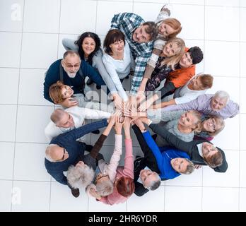 Gruppe älterer Menschen, die aus ihren Händen einen Turm bauen. Stockfoto