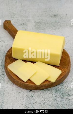 Kashar-Käse oder Kashkaval-Käse auf steinernem Hintergrund. Cheddar-Käse In Scheiben Stockfoto