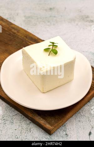 Feta-Käse mit Kräutern auf steinernem Hintergrund. Nahaufnahme des Frühstückskäses Stockfoto