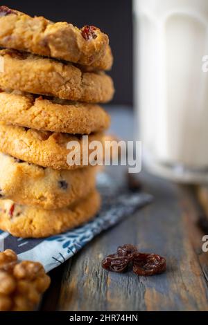 Köstliche frisch gebackene hausgemachte Kekse mit Schokoladenstückchen Glas Milch auf einem Gestell in der Nähe und schwarzem Hintergrund gestapelt. Stockfoto