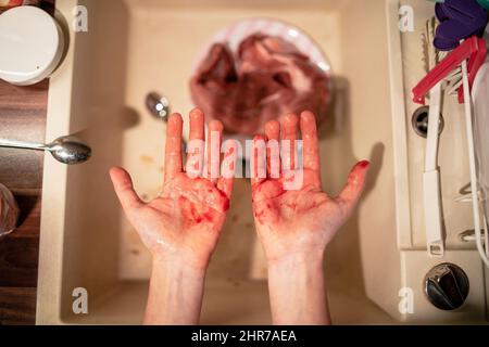 Draufsicht auf zwei Hände, die mit Blut bedeckt sind Stockfoto
