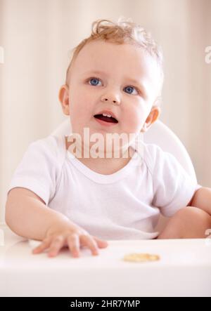 Bereit zum Einfüttern. Ein süßes Baby, das in einem Babystuhl sitzt. Stockfoto