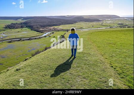 Brighton UK 25. February 2022 - Ein Spaziergänger genießt die Aussicht über den Fluss Cuckmere und das Tal unterhalb von Alfriston , Sussex an einem schönen sonnigen Tag : Credit Simon Dack / Alamy Live News Stockfoto