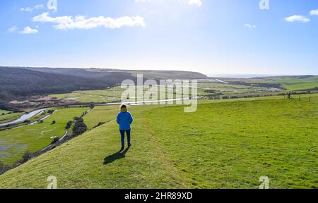 Brighton UK 25. February 2022 - Ein Spaziergänger genießt die Aussicht über den Fluss Cuckmere und das Tal unterhalb von Alfriston , Sussex an einem schönen sonnigen Tag : Credit Simon Dack / Alamy Live News Stockfoto