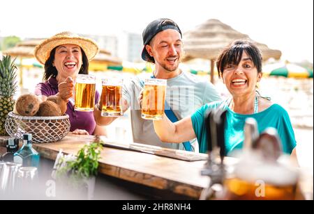 Freunde gemischter Altersgruppen genießen Bier in der Strandbar Chiringuito - Freundschaftsleben mit fröhlichen Menschen, die beim Sommerfest Zeit miteinander verbringen Stockfoto