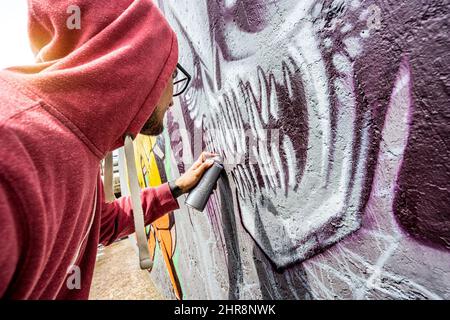 Straßenkünstler Malerei bunte Graffiti an der öffentlichen Wand - modern Kunstkonzept mit Urban Guy Performing und Vorbereitung live murales Mit mehrfarbigem aer Stockfoto