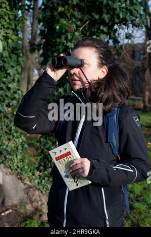 London, Großbritannien - Januar 5. 2022: Personenvogelbeobachtung mit Ferngläsern und Nachschlagewerk Stockfoto