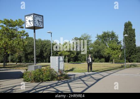 Öffentliche Uhr und männliche Figur stehend, stehender Mann - Sean Henry - 2015 im Süd-Bahnhof in Eschborn, Hessen, Deutschland Stockfoto