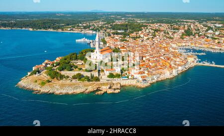 Stadt Rovinj mit dem hohen Turm der Kirche St. Euphemia. Kroatische Stadtgebäude mit roten Dächern auf der Halbinsel, umgeben von der Adria. Luftpanorama Stockfoto
