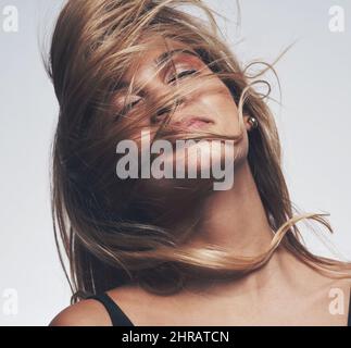 Ein guter Friseur kann Ihr Haar und Ihre Stimmung zu beheben. Aufnahme einer Frau, die ihr Gesicht bedeckt, während sie vor einem grauen Hintergrund posiert. Stockfoto