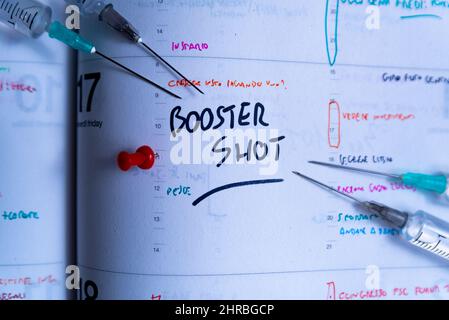 Impfkampagne gegen Covid mit Auffrischungsimpfung und Jab-Konzept auf der Tagesordnung. Spritze auf Kalender mit als Konzept für die vierte Covid-19-Impfstoffdosis zum Kampf Stockfoto