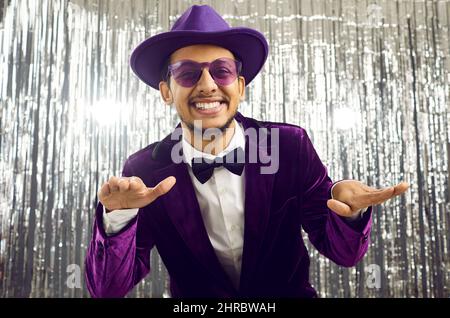 Fröhlicher junger Kerl in original lila Cord Smoking gekleidet mit Spaß auf silbernem Hintergrund. Stockfoto