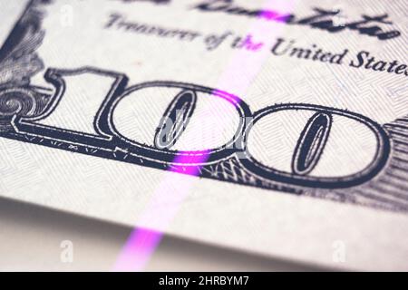Überprüfung von Dollarnoten im UV-Licht. Fälschungsgeld-Konzept. Fragment der Vorderseite der 100 einhundert-Dollar-Banknote. Neue Probe Stockfoto