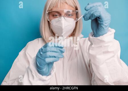 Coronavirus-pcr-Test. Arzt in Schutzanzug medizinische Maske Handschuhe hält Abstrich Speichel Probe für diagnostische covid 19 Coronavirus-Virus auf blauem Rücken Stockfoto