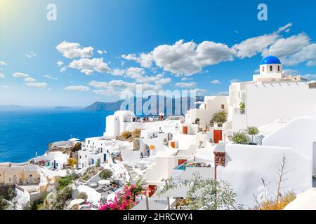 Blick von einer weiß getünchten Terrasse auf die Caldera, das Meer und das Dorf Oia, Santorini, Griechenland, mit einer der berühmten Kirchen mit blauer Kuppel im Blick. Stockfoto