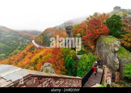 Touristen fotografieren aus dem Kloster von St. Barbara oder Roussanou in Meteora, Griechenland unter nebligen Himmel im Herbst. Stockfoto