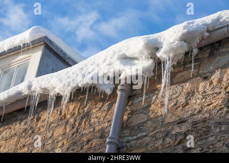 Eiszapfen, die am Rand eines Hausdachs in England, Großbritannien, hängen Stockfoto