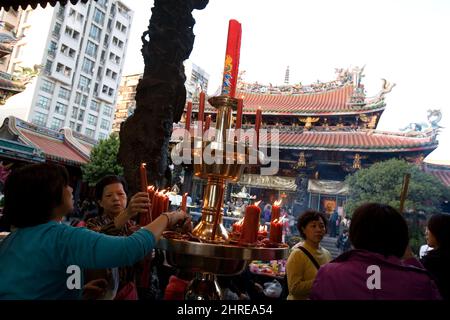 Menschen zünden Kerzen im Bangka Lungshan Tempel an, einem buddhistischen Tempel im Wanhua Bezirk von Taipei, Taiwan Stockfoto