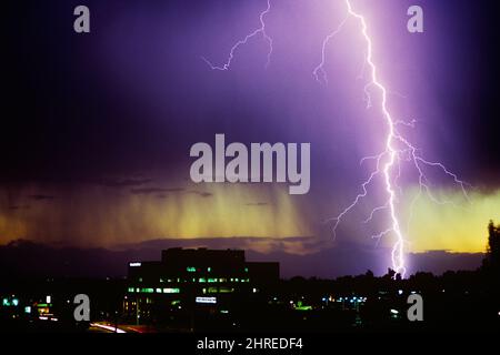 1990S EINFACHER BLITZ WÄHREND EINES GEWITTERS MIT REGENWASSER, DAS AUS EINER DUNKLEN WOLKE ÜBER GEBÄUDEN FÄLLT COLORADO USA - KL17562 ARM001 HARS A KONZEPTUELLER GEWITTERBOLZEN BLITZ HOCHSPANNUNGS-STÜRME TREFFEN ATMOSPHÄRENBOLZEN COLORADO-ENTLADUNG WÄHREND EINES ELEKTROSTATISCHEN ALTMODISCHEN PLASMABONERS Stockfoto