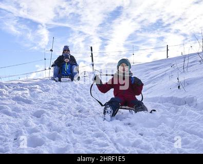 Mama und ihre Kinder rutschen an einem Wintertag im Kowalowe Wzgorze Resort mit Schlitten einen Hügel hinunter Stockfoto