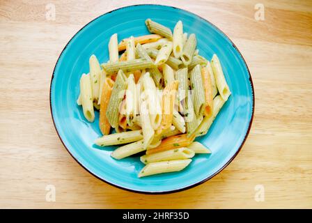 Teller gekochte zylinderförmige Penne Pasta Nudeln in drei Farben Gelb, Grün und Rot Stockfoto