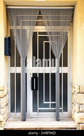Weiße Aluminium-Tür mit geometrischen Details und weißem Vorhang Stockfoto