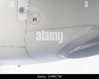 Fragment eines Flugzeugflügels mit Nähten und metallischen Schrauben. Blick vom Bullauge Stockfoto