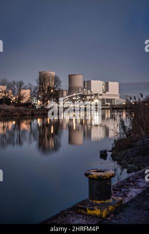 Im Vordergrund verwischte der Kai im Hintergrund ein Kohlekraftwerk Stockfoto