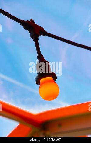 Nahaufnahme einer roten oder orangefarbenen festogenen Glühbirne am blauen Himmel im Café Billy Winters am Portland Beach Stockfoto