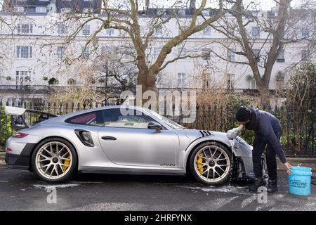 Ein Autowaschmann reinigt einen luxuriösen Porsche auf dem Chester Square in London SW1, wo eine Reihe russischer Immobilienbesitzer - darunter Roman Abramovich - investiert haben sollen - und nach der russischen Invasion der Ukraine, jetzt am zweiten Tag, Am 25.. Februar 2022 wurden in London, England, weitere Sanktionen gegen russische Handelsinteressen im Vereinigten Königreich angekündigt. Die Kampagnengruppe „Transparency International“ sagt, dass geschätzte 1,5bn £von britischen Immobilien über die City of London, den Finanzbezirk der britischen Hauptstadt, mit verdächtigen Mitteln aus Russland ausgegeben wurden. (Foto von Richard Baker / in Bildern via Ge Stockfoto