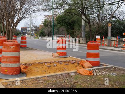 SAN ANTONIO, TX - 25. JAN 2020: Orangefarbene Warnfässer auf einer Straßenbaustelle, auf der Autos auf der Straße vorbeifahren. Stockfoto