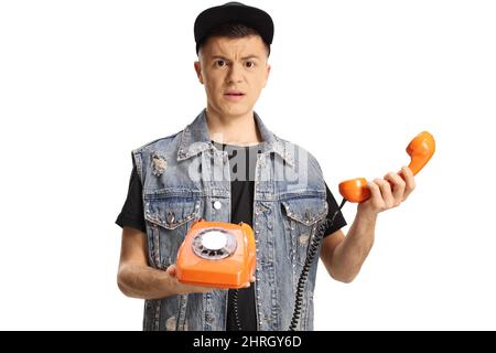 Verwirrt junger Mann mit einem orangefarbenen Drehtelefon isoliert auf weißem Hintergrund Stockfoto