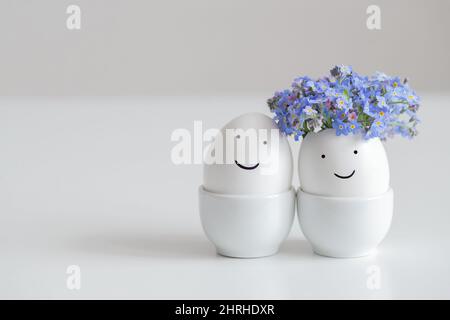 Ein paar lustige Eier mit bemalten Gesichtern auf weißem Hintergrund. Ostereier mit Blumen. Liebeskonzept. Platz für Text. Stockfoto