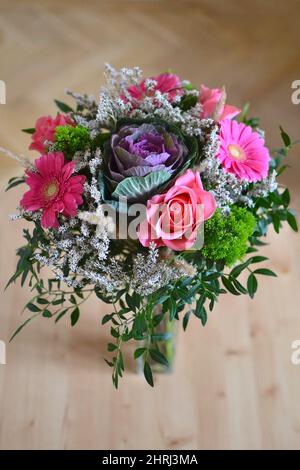 Blumen, Blumensträuße, florale Zusammensetzung besteht aus rosa Rosen, rosa Gerberas, Zierkohl, Zierblatt, Limonium californicum. Holzbalkett Stockfoto