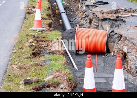 Rohr und Kabel in einem Graben, der auf einer Baustelle entlang einer Straße gegraben wurde Stockfoto