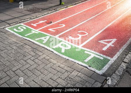 Laufstrecken, die auf der Oberfläche einer gepflasterten Fußgängerzone im Stadtzentrum gemalt sind. Neues Start-Konzept. Stockfoto