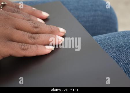 Nahaufnahme der Hände einer afroamerikanischen Frau, die in einem schwarzen Buch Braille liest Stockfoto