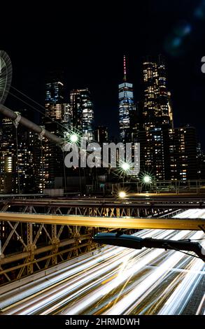 Vertikale Aufnahme einer berühmten Brooklyn-Brücke und Stadtbild auf der Rückseite, aufgenommen während der Nacht Stockfoto