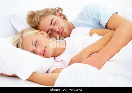 Schlafend in seinen Armen. Ein junges Paar schläft schnell im Bett zusammen. Stockfoto
