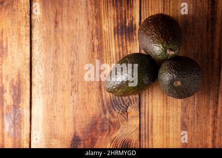 Mexikanische Avocado (Persea americana) auf rustikalem Holztisch. Hauptbestandteil zur Zubereitung von Guacamole. Obere VIEWimage mit Kopierbereich. Stockfoto