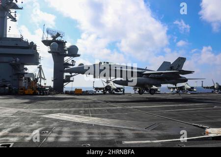 PHILIPPINISCHES MEER (Feb 24, 2022) Konteradmiral J.T. Anderson, Kommandant der Carrier Strike Group 3, bereitet sich auf eine verhaftete Landung in einem F/A-18E Super Hornet vor, das den „Tophattern“ des Strike Fighter Squadron (VFA) 14 auf dem Flugdeck des Nimitz-Klasse-Flugzeugträgers USS Abraham Lincoln (CVN 72) zugewiesen wurde. Die Abraham Lincoln Strike Group befindet sich im geplanten Einsatzgebiet der US-Flotte für 7., um die Interoperabilität durch Allianzen und Partnerschaften zu verbessern und gleichzeitig als reaktionsfähige Truppe zur Unterstützung einer freien und offenen Region im Indo-Pazifik-Raum zu dienen. (USA Navy Foto von Mass Communi Stockfoto
